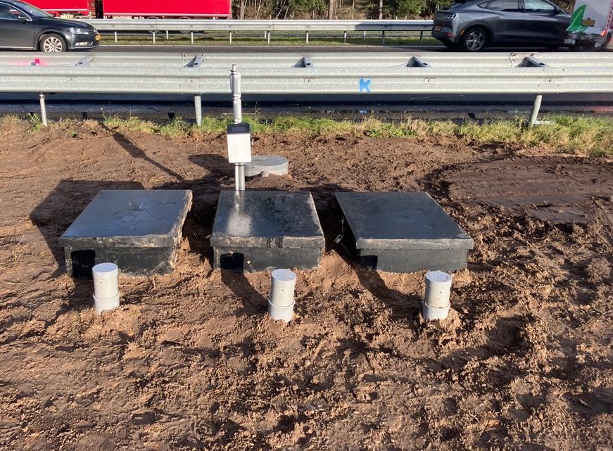 Drie zwarte dozen met watermeetsysteem er in langs de snelweg A58.