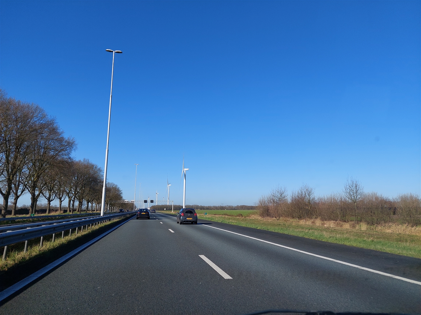 de snelweg A58 met auto's en windmolens aan de linkerkant